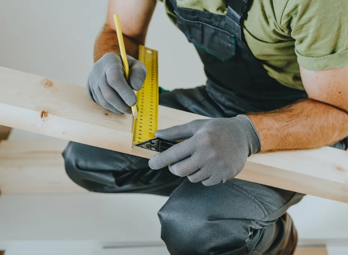 a man taking a measurement on a piece of wood