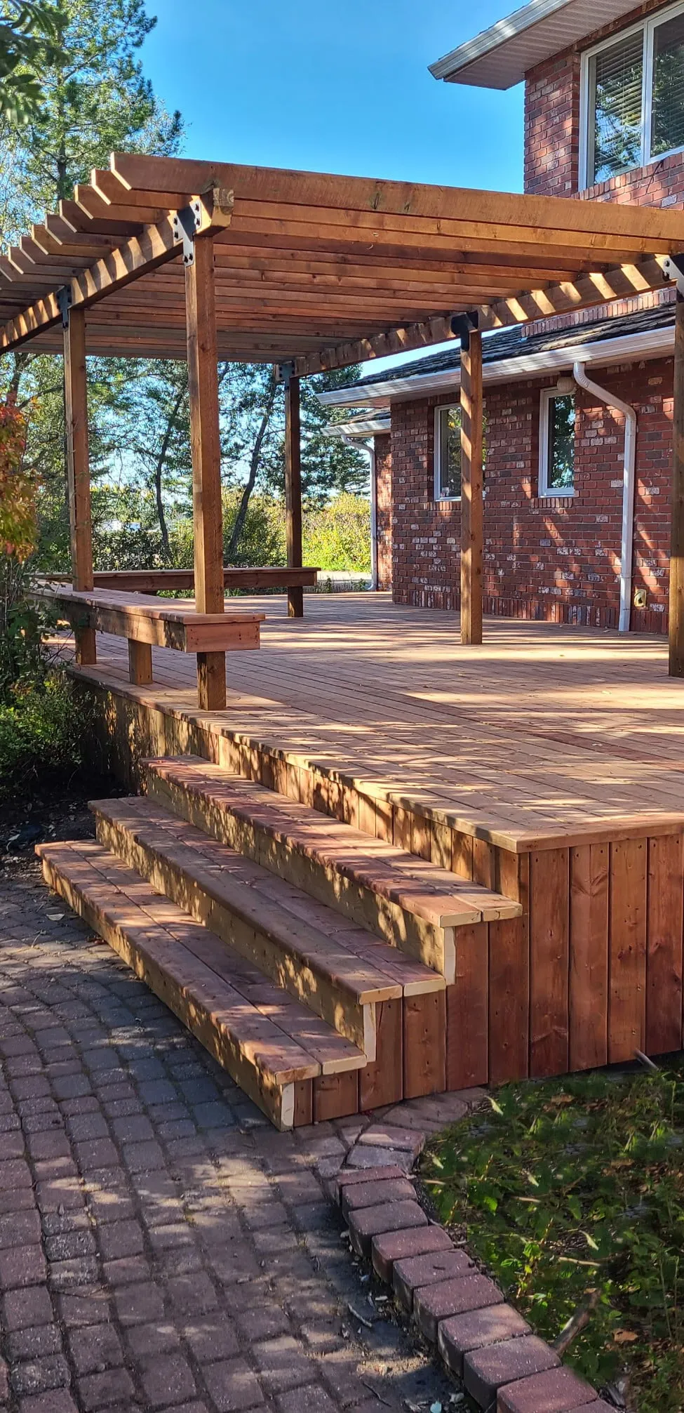 a deck with a pergaloa on the back of a house