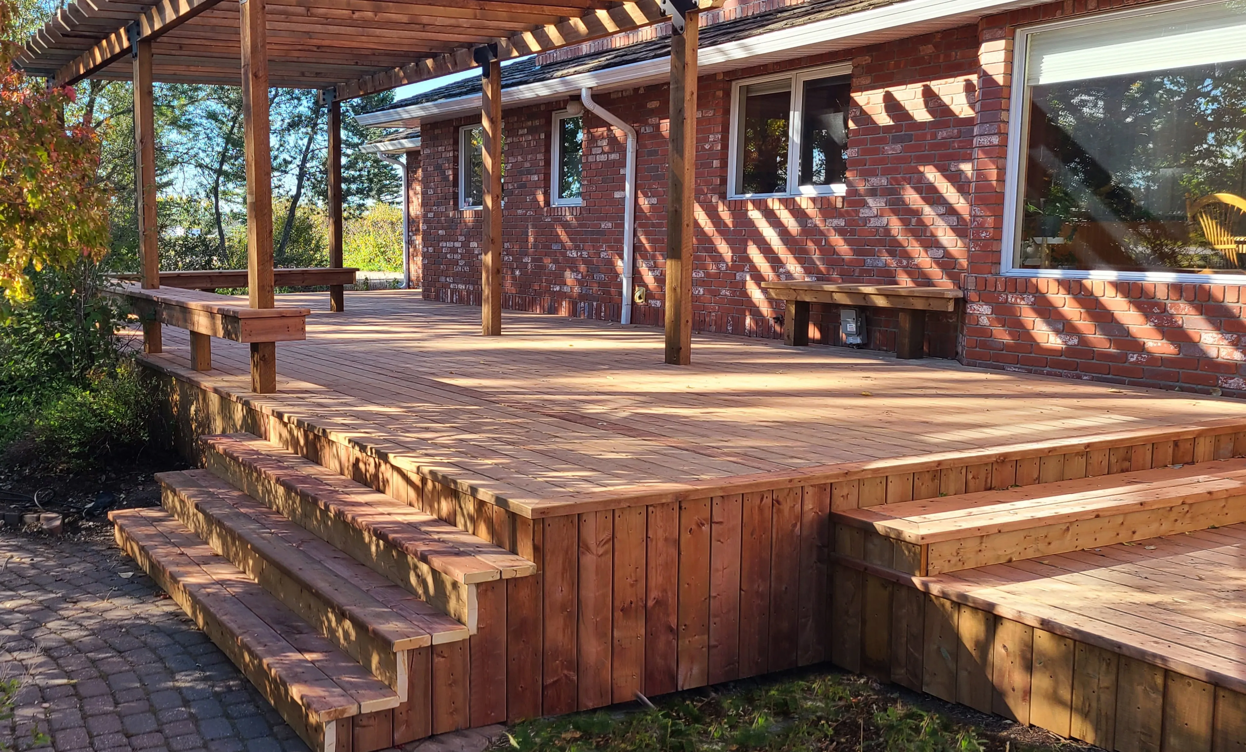 a deck with a pergaloa on the back of a house