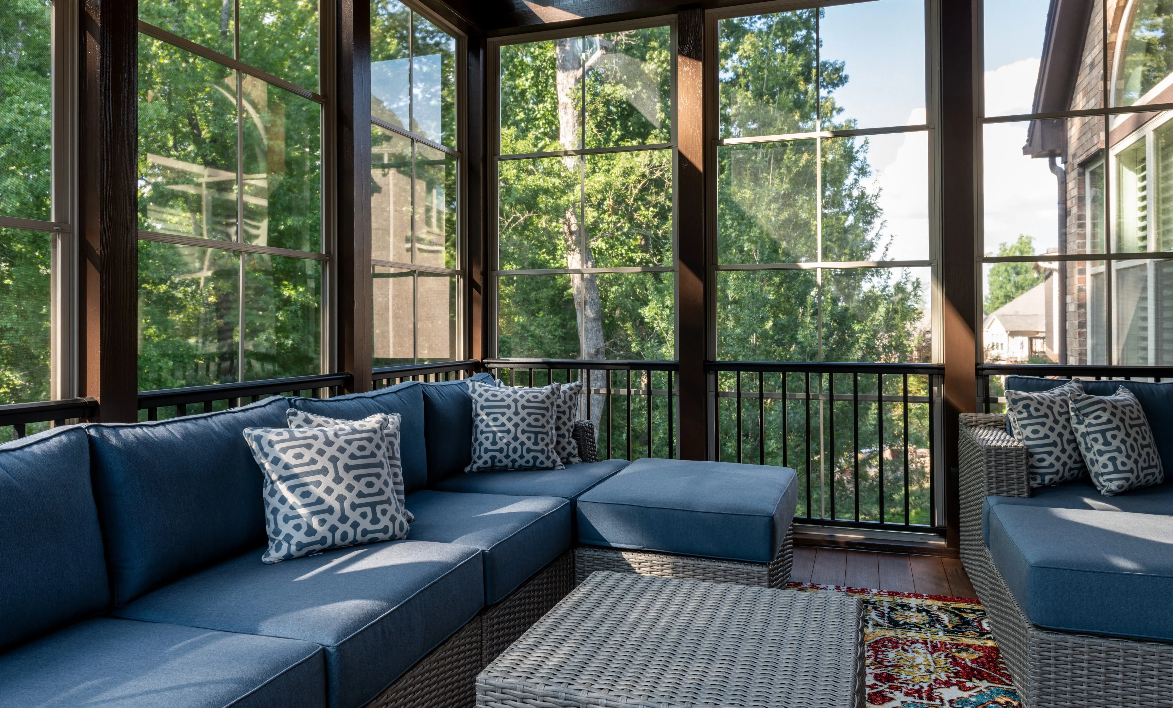 A sunroom with a couch and trees outside the windows