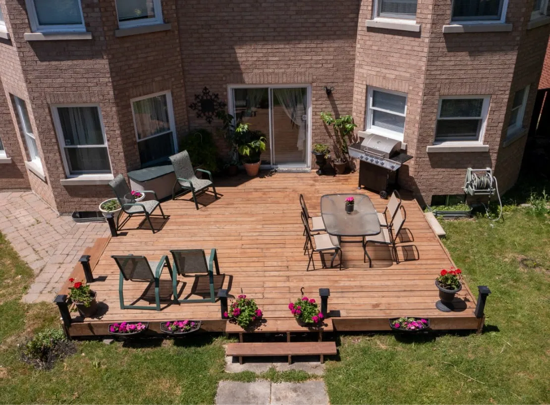 a low level flat deck in a backyard of a red bricked home.