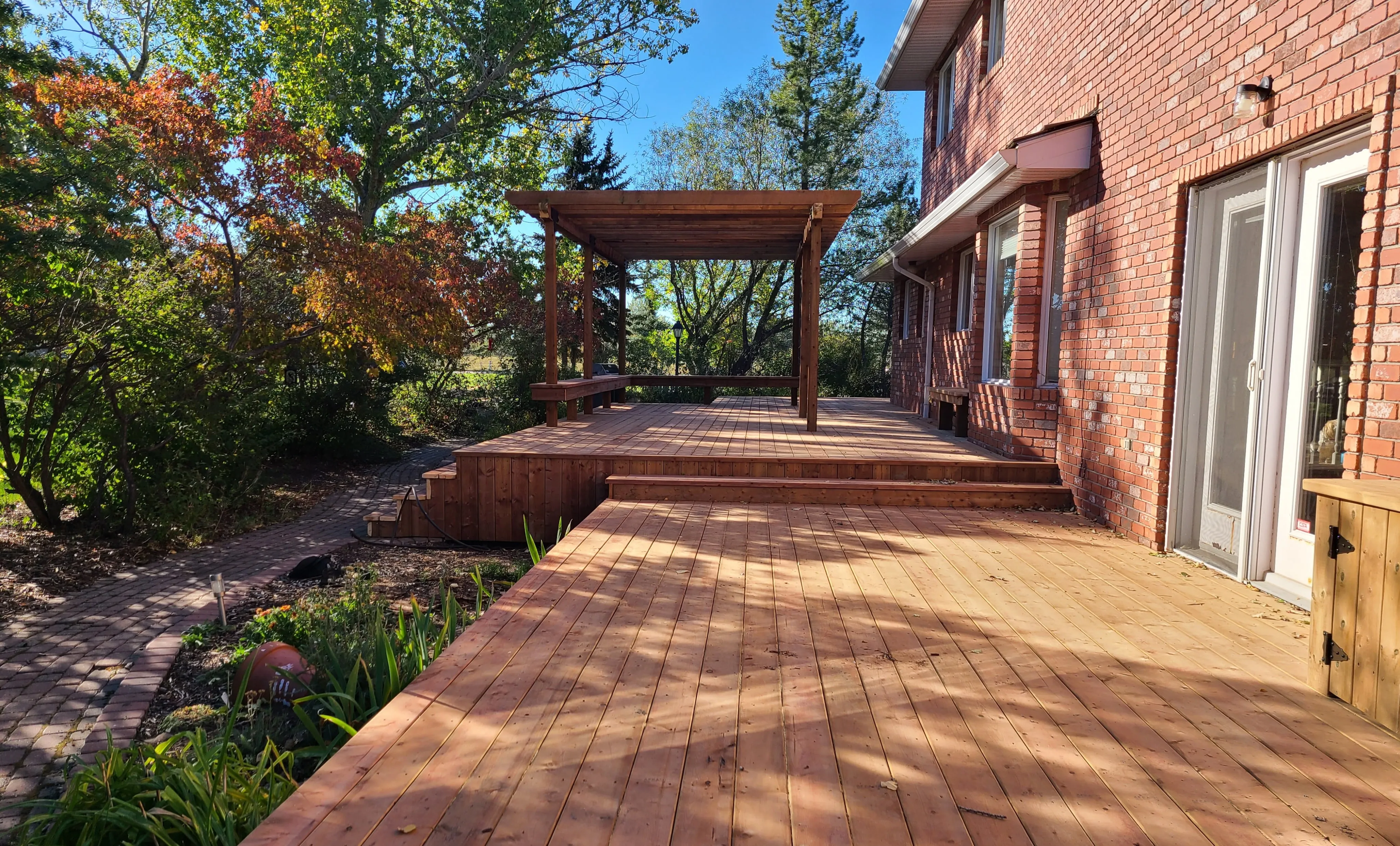 a deck in the backyard of a red brick home