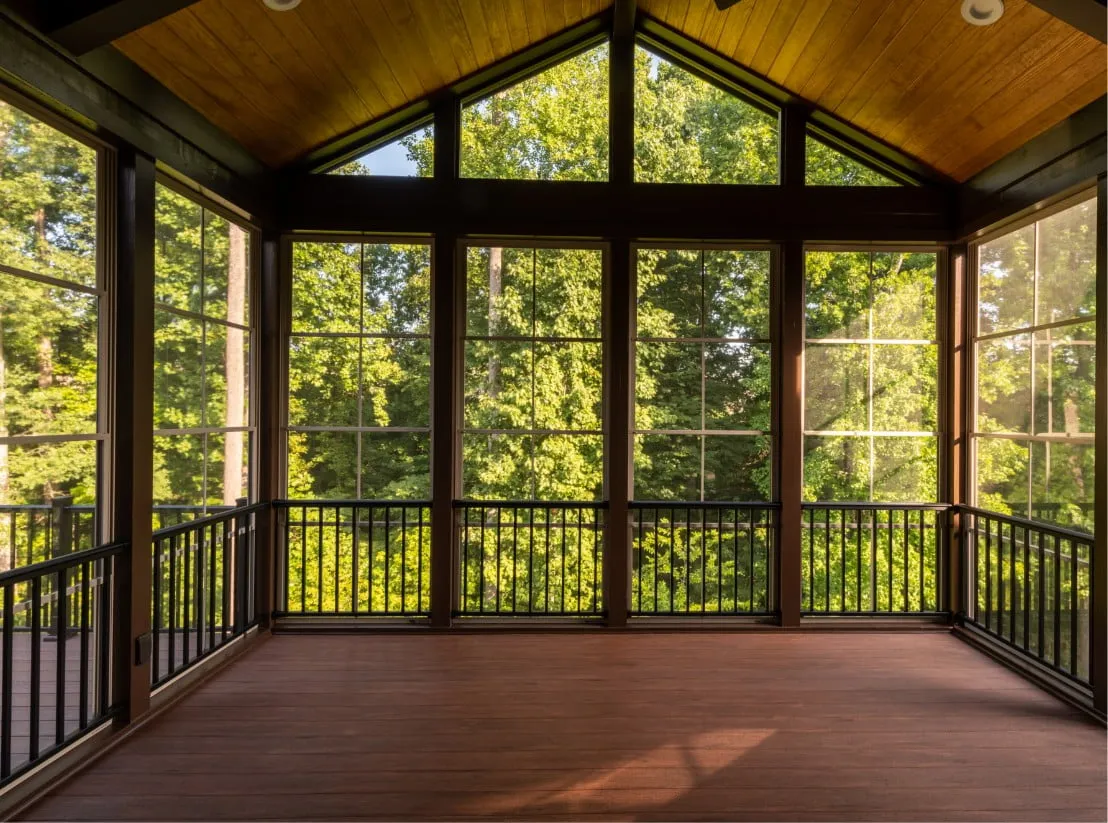 a picture of an empty sunroom just built. There is a huge forest outside the windows